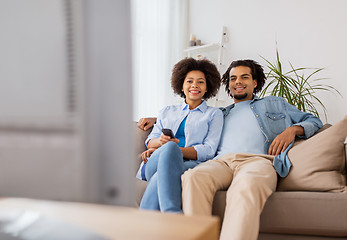 Image showing smiling couple with remote watching tv at home