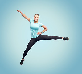 Image showing happy smiling sporty young woman jumping in air