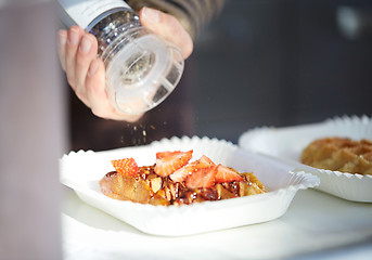 Image showing close up of hand with spice mil spicing waffle