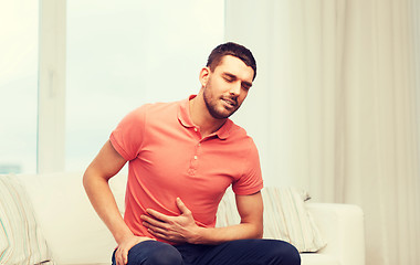 Image showing unhappy man suffering from stomach ache at home