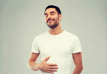 Image showing happy full man touching tummy over gray background