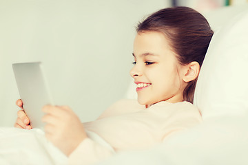 Image showing happy girl lying in bed with tablet pc at home