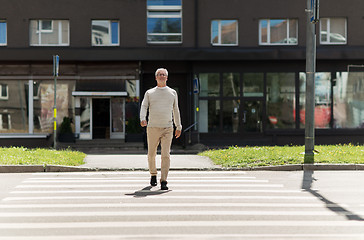 Image showing senior man walking along city crosswalk