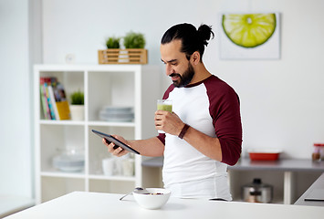 Image showing man with tablet pc eating breakfast at home