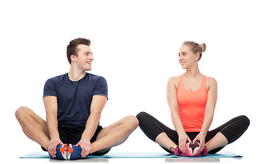 Image showing happy sportive man and woman sitting on mats
