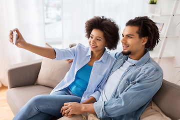 Image showing happy couple with smartphone taking selfie at home