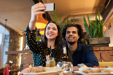 Image showing happy couple taking selfie at cafe or bar