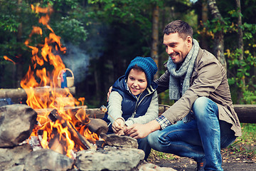 Image showing father and son roasting marshmallow over campfire