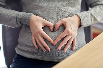 Image showing pregnant woman making heart shape at office