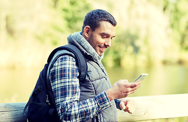 Image showing happy man with backpack and smartphone outdoors