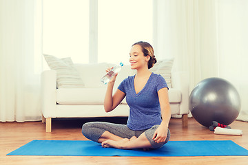 Image showing happy woman with water bottle exercising at home