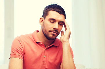 Image showing unhappy man suffering from headache at home