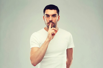 Image showing young man making hush sign over gray background