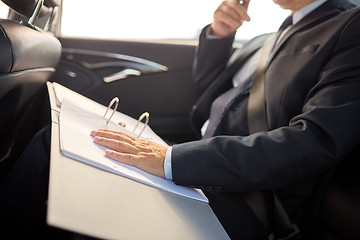 Image showing senior businessman with papers driving in car