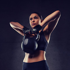 Image showing young woman flexing muscles with kettlebell in gym