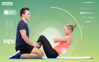 Image showing happy sportive man and woman doing sit-ups