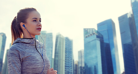 Image showing happy woman with earphones running in city