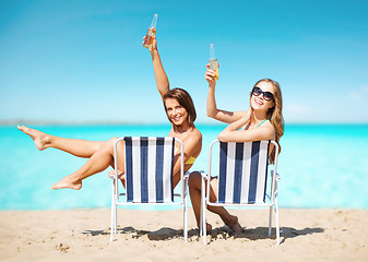 Image showing happy young women with drinks sunbathing on beach