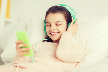 Image showing happy girl lying in bed with smartphone at home