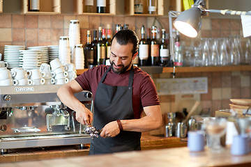 Image showing barista with holder and tamper making at coffee