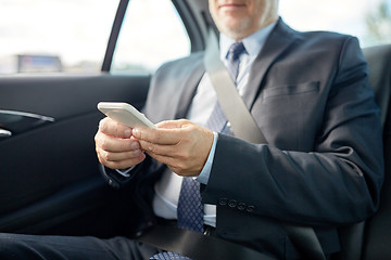 Image showing senior businessman texting on smartphone in car