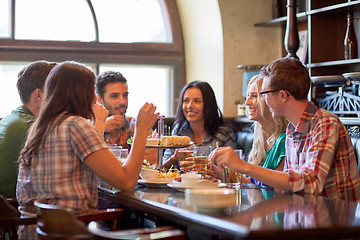 Image showing happy friends eating and drinking at bar or pub