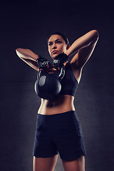 Image showing young woman flexing muscles with kettlebell in gym