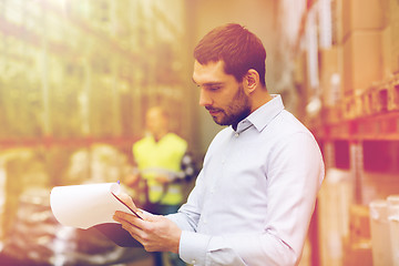 Image showing businessman writing to clipboard at warehouse