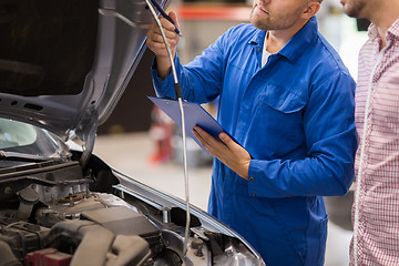 Image showing auto mechanic with clipboard and man at car shop