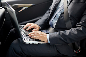 Image showing senior businessman with laptop driving in car