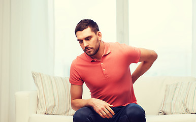 Image showing unhappy man suffering from backache at home