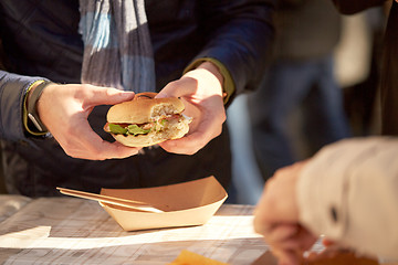 Image showing hands of man eating hamburger outdoors