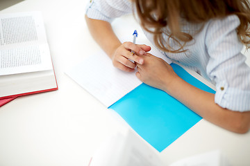 Image showing girl with book writing to notebook at school