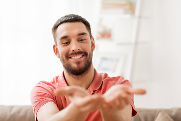 Image showing happy man holding something imaginary at home