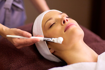 Image showing beautician applying facial mask to woman at spa