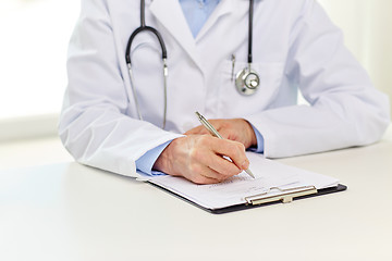 Image showing senior doctor with clipboard writing at hospital