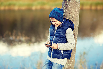 Image showing happy boy playing game on smartphone outdoors