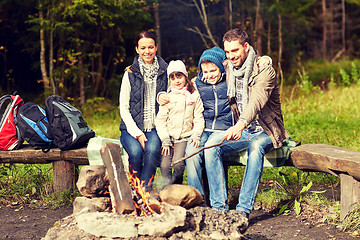 Image showing happy family sitting on bench at camp fire