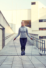 Image showing happy woman exercising with jump-rope outdoors