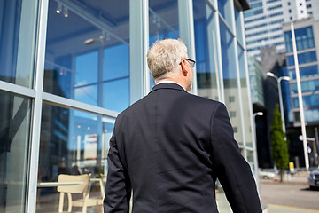 Image showing senior businessman walking along city street