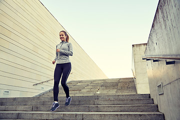 Image showing happy sporty woman running downstairs in city