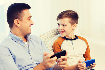 Image showing happy father and son with smartphones at home