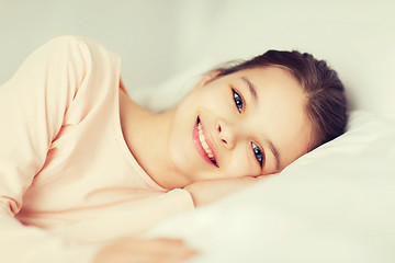 Image showing happy smiling girl lying awake in bed at home