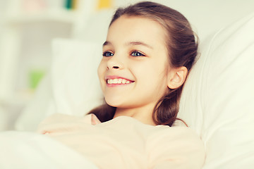 Image showing happy smiling girl lying awake in bed at home