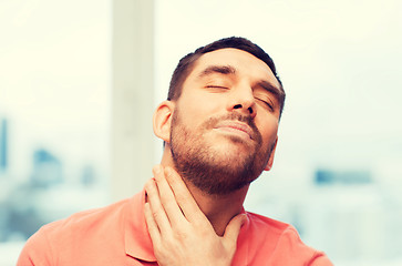 Image showing unhappy man suffering from throat pain at home