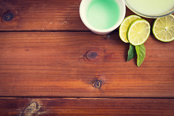 Image showing close up of body lotion, cream and limes on wood