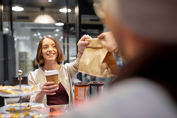 Image showing woman taking paper bag from seller at cafe