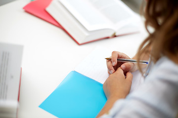 Image showing girl with book writing to notebook at school