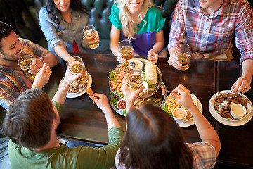 Image showing happy friends eating and drinking at bar or pub