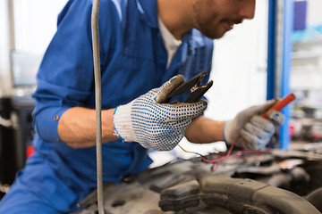 Image showing auto mechanic man with cleats charging battery